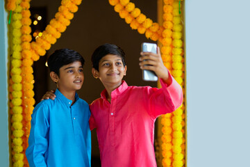 Wall Mural - Indian little boys using smartphone and enjoying diwali festival.