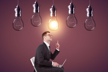 Poster - Young european businessman using laptop and pointing at abstract glowing row of light bulbs on red background. Idea, solution and innovation concept.