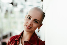 Smiling Young Bald Woman Leaning On Wall