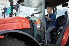 Boy Looking Away While Driving Tractor On Farm