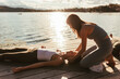 © Westend61 - Female instructor assisting women lying down on jetty during yoga class