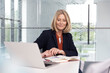 © Westend61 - Blond businesswoman reading diary at desk in office