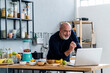 © Westend61 - Man preparing smoothie while learning through laptop in kitchen
