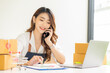 © ArLawKa - Portrait of a Small Business Startup, SME Owner, Asian Female Entrepreneur Work on receipt boxes and check online orders to prepare the boxes. Selling to customers. Online SME business idea.