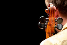 A View From Behind Of A Cello Player Sitting And Having His Instrument Leaning On His Shoulder Making Only The Scroll And Pugs Visible