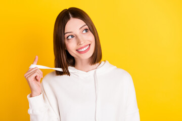 Wall Mural - Photo of cheerful curious lady look empty space think thoughts wear white sweatshirt isolated yellow color background
