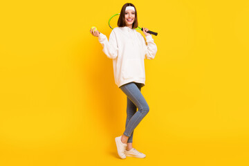 Wall Mural - Photo of sportive lady hold racket ball wear white headband sweatshirt jeans shoes isolated yellow color background