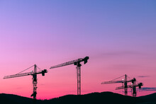 Silhouette Cranes At Construction Site Against Sky During Sunset