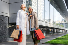 Smiling Women Looking Away While Holding Shopping Bags Outside Mall