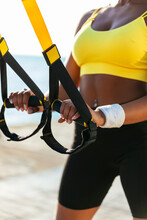 Young Female Athlete Holding Suspension Straps On Sunny Day
