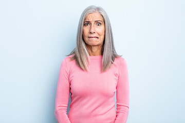 Wall Mural - middle age gray hair woman looking puzzled and confused, biting lip with a nervous gesture, not knowing the answer to the problem
