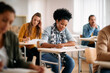 © Drazen - African American female student writes while learning during class at university classroom.