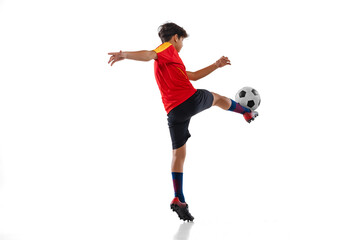 Wall Mural - Full-length portrait of boy, male soccer football player training isolated on white background. Toe punt