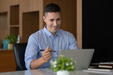 Wall Mural - smiling businessman having virtual team meeting call, talking, remotely working at home watching online learning training webinar in remote office