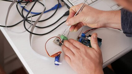 a male programmer creates robotics, an arduino board controls servo motors. diy mechanics, programmi