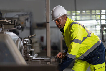 Wall Mural - Male engineer worker maintenance heavy machine in the factory. Black male worker working with heavy machine with safety uniform, goggles and helmet