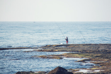 Wall Mural - A fisherman with a fishing rod by the sea