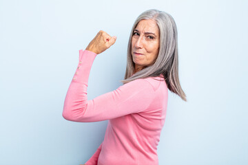 Wall Mural - middle age gray hair woman feeling happy, satisfied and powerful, flexing fit and muscular biceps, looking strong after the gym