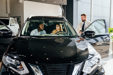 Poster - Multi ethnic couple choosing new car at modern showroom