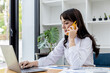 © kamiphotos - Beautiful Asian businesswoman talking on mobile phone and using laptop, concept image of Asian business woman working smart, modern female executive, startup business woman, business leader woman.