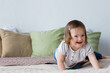 © LIGHTFIELD STUDIOS - Happy child with down syndrome looking away on bed at home.