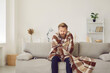 © Studio Romantic - It's cold at home in wintertime. Man freezing in his house in winter because of broken thermostat. Sad bearded young guy wrapped in woolen plaid shivering while sitting on sofa in living room interior