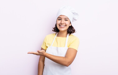 Wall Mural - pretty young woman smiling cheerfully, feeling happy and showing a concept. chef concept