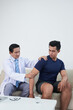 © DragonImages - Vertical medium long shot of mature Asian medical worker examining patients joints range of motion