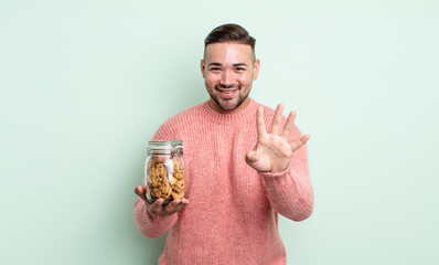 Wall Mural - young handsome man smiling and looking friendly, showing number four. cookies bottle concept