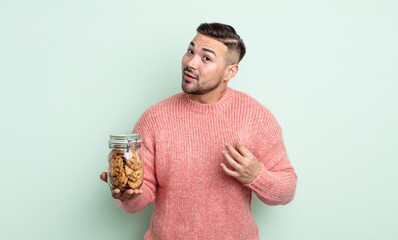 Wall Mural - young handsome man looking arrogant, successful, positive and proud. cookies bottle concept