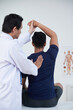 © DragonImages - Vertical medium back view shot of modern mature osteopathic therapist treating young man manipulating his bones, muscles and fasciae