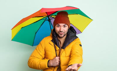 Wall Mural - young handsome man smiling happily with friendly and  offering and showing a concept. rain and umbrella concept