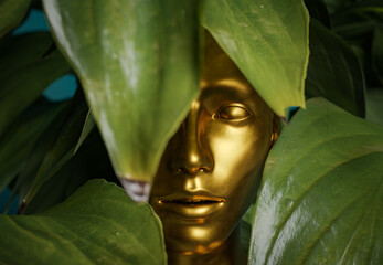 golden female statue with leaves around