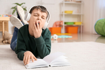 Sticker - Sleepy little boy with book and headphones at home