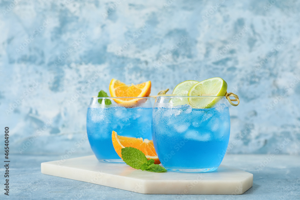 Glasses of Blue Lagoon cocktail on color background
