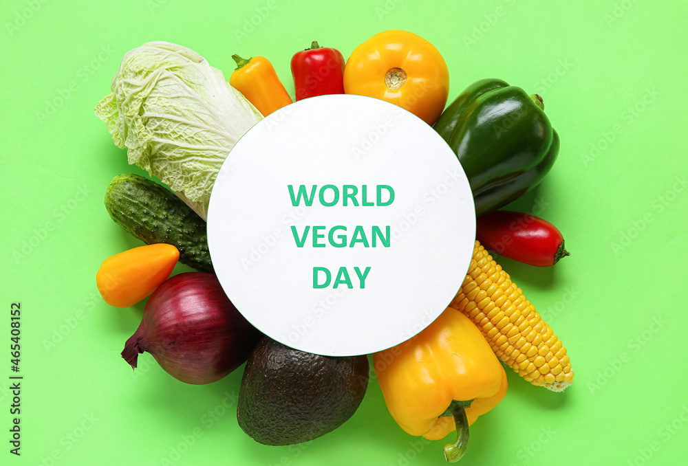 Different vegetables and card with text WORLD VEGAN DAY on color background