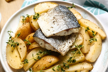 Tasty sea bass fish with potatoes on table, closeup