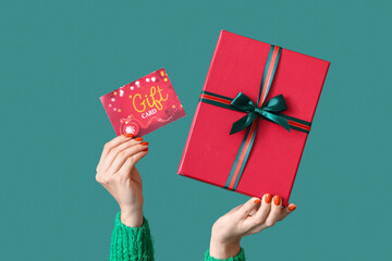 Woman with Christmas present and gift card on green background