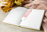 Fototapeta  - Blank open book with bookmark and oak leaves on light background