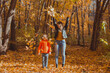 © satura_ - Single parent family playing with autumn leaves in park. Happy mom and son throw autumn leaves up in fall park.
