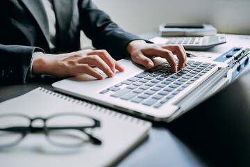 Wall Mural - Close up of Businesswomen or Accountant working on laptop computer with analytic business report graph and finance chart at the workplace, financial and investment concept.