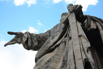 The Apostle Paul with his sword drawn in his hand. Old giant statue in front of the Basilica of Saints Peter and Paul in EUR district, Rome. Low angle view on cloudy sky.