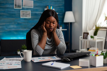 Poster - African american woman doing remote work for business project with data charts, feeling tired. Entrepreneur working from home with computer and analysis papers on desk. Sleepy worker