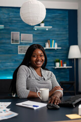Poster - Portrait of cheerful person sitting at desk with computer, working from home on business project. Young woman looking at camera and using monitor with keyboard to do remote work.
