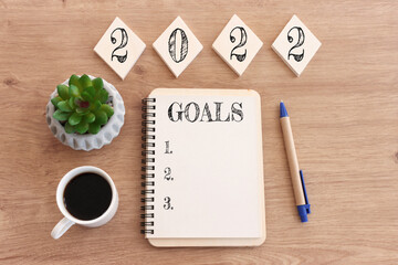 Wall Mural - Business concept of top view 2022 goals list with notebook, cup of coffee over wooden desk