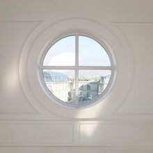 Round Window Overlooking The City In The White Wall.