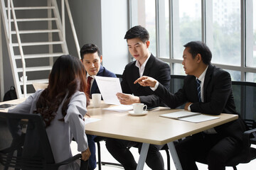 asian executive leader discussion with colleague in meeting on window in office . adult businessman manager talking and advise to group of coworkers or table in conference . boss training in morning.