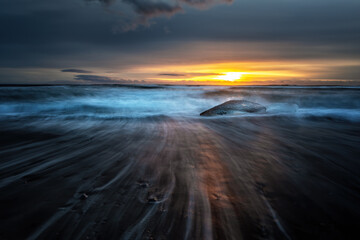 Wall Mural - Sunrise on Diamond Beach, Southeast Iceland. Sunlight catches large chunks of ice that have moved out from the nearby Jokulsarlon glacial lagoon.