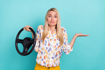 Photo of unsure young blond lady drive shrug shoulders wear printed blouse isolated on teal color background