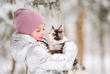 Little Girl Carries Cat In Her Arms In A Snowy Winter